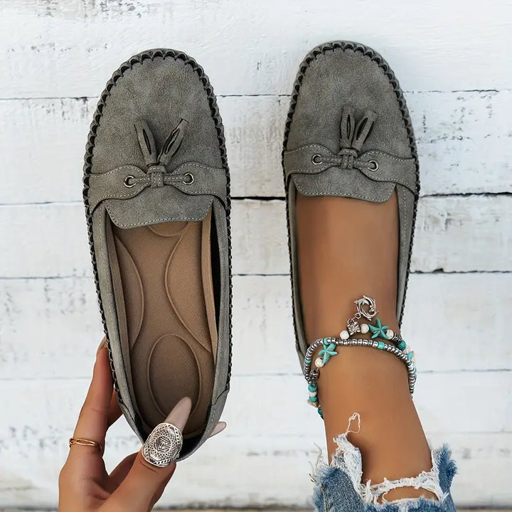Vue de dessus des mocassins gris, mettant en valeur leur design élégant avec un petit nœud décoratif et des œillets en métal. L&