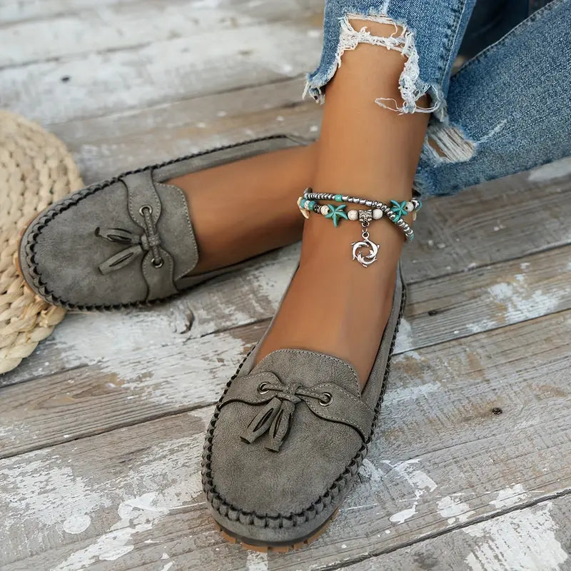 Mocassins gris en cuir doux avec un petit nœud décoratif, parfaits pour un style décontracté et élégant. La semelle robuste assure confort et durabilité, tandis que les détails de couture ajoutent une touche raffinée. Ces mocassins sont idéaux pour une allure chic et un confort optimal au quotidien.