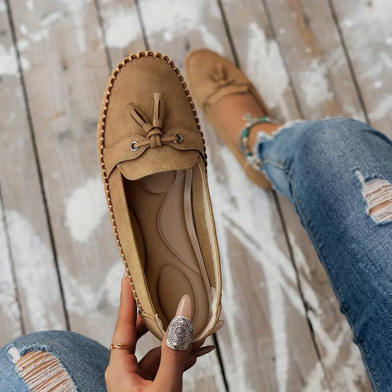 Vue de dessus des mocassins beiges, mettant en valeur le design simple mais raffiné avec un petit nœud décoratif et des œillets en métal. L&