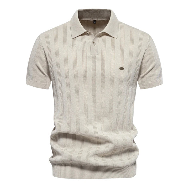 Polo tricot beige à rayures fines avec un col classique et un logo discret sur la poitrine. Ce modèle est idéal pour un look élégant et léger, parfait pour les journées d&