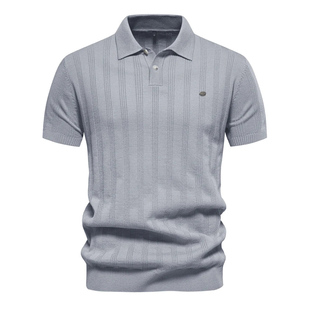 Polo tricot bleu clair à rayures fines, avec un col classique et un logo discret sur la poitrine. Un vêtement léger et raffiné, idéal pour apporter une touche d&