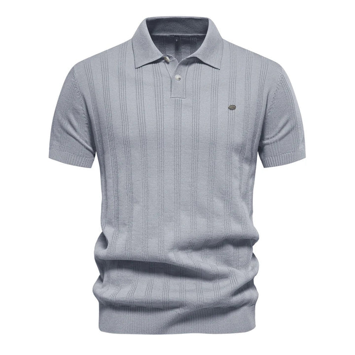 Polo tricot bleu clair à rayures fines, avec un col classique et un logo discret sur la poitrine. Un vêtement léger et raffiné, idéal pour apporter une touche d&