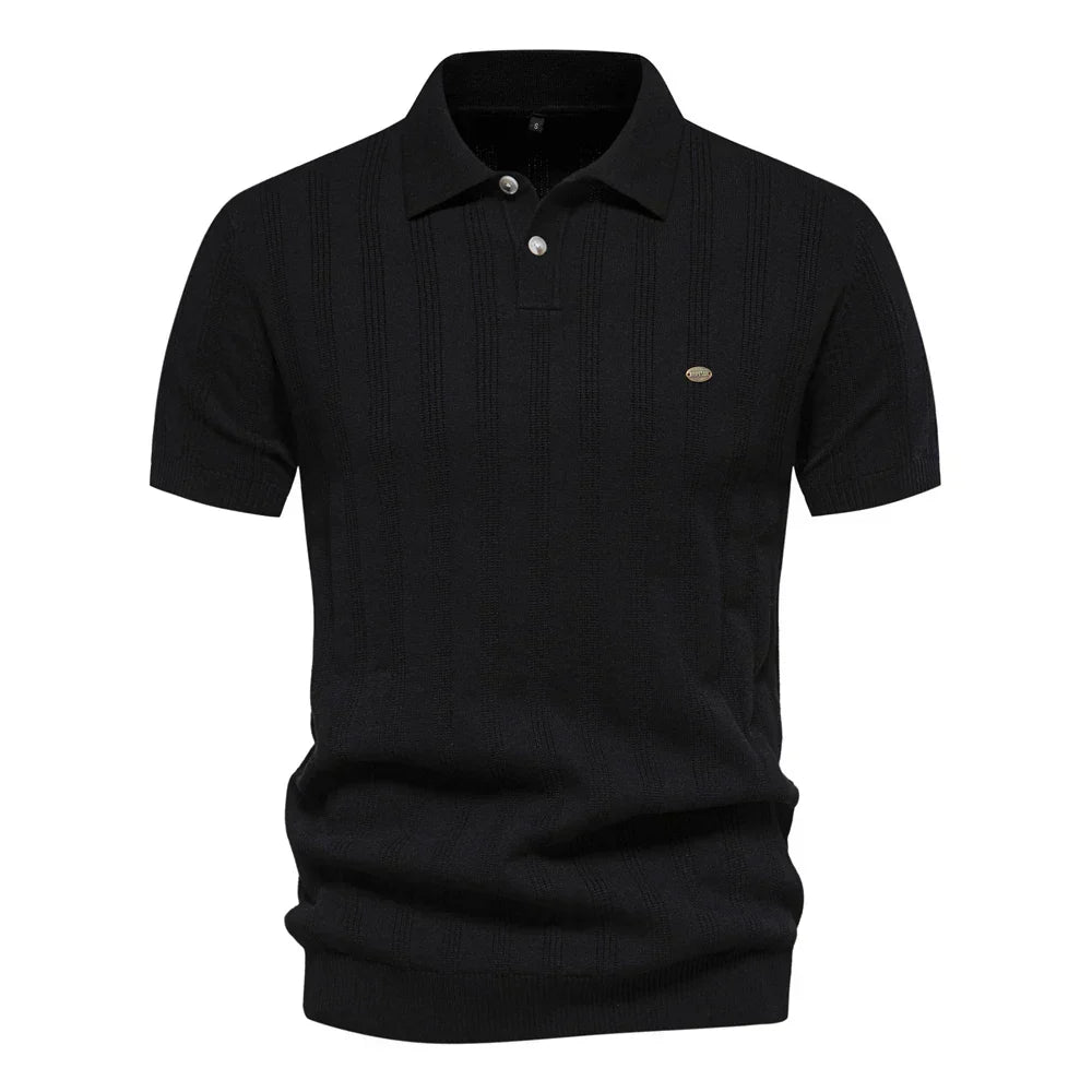 Polo tricot noir à rayures discrètes, avec un col classique et un logo sur la poitrine. Un modèle chic et confortable, idéal pour la saison estivale.
