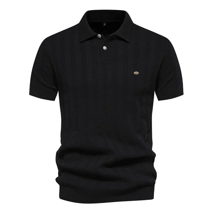 Polo tricot noir à rayures discrètes, avec un col classique et un logo sur la poitrine. Un modèle chic et confortable, idéal pour la saison estivale.