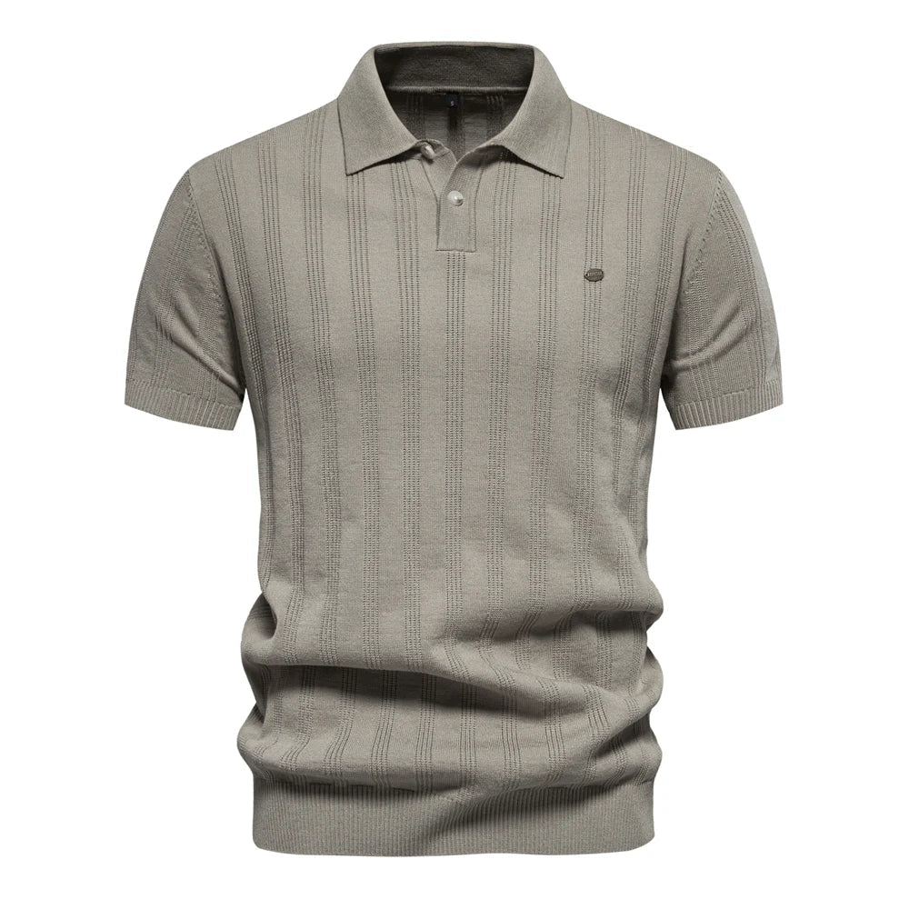 Polo tricot beige clair à rayures subtiles, avec un col classique et un petit logo sur la poitrine. Un choix parfait pour les journées estivales, alliant confort et élégance.