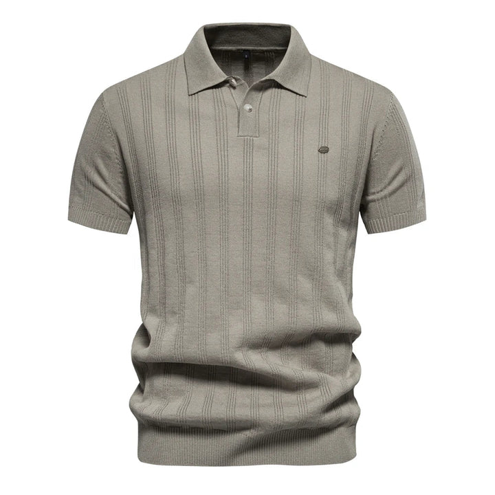 Polo tricot beige clair à rayures subtiles, avec un col classique et un petit logo sur la poitrine. Un choix parfait pour les journées estivales, alliant confort et élégance.