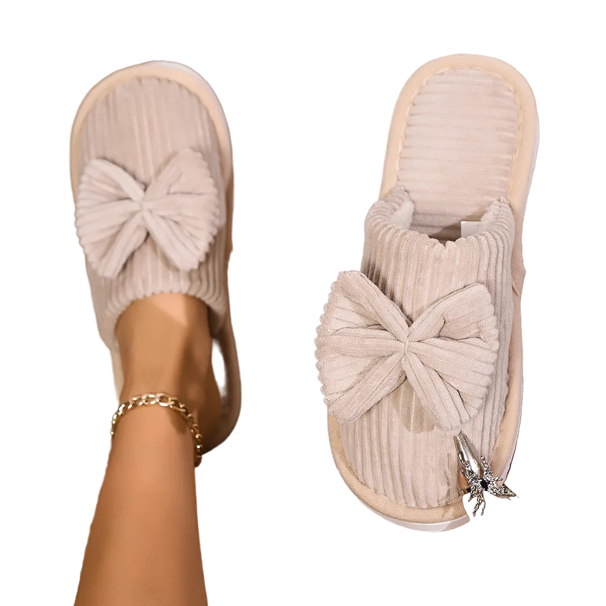 Chaussons femme beiges en velours côtelé avec grand nœud sur le dessus, intérieur doux et confortable. Photo portée, avec un chausson au pied et l’autre tenu à la main, idéal pour garder les pieds bien au chaud à la maison.