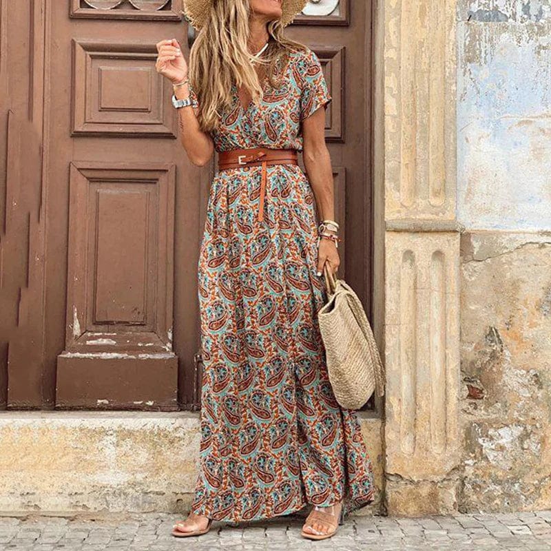 Robe maxi boho femme Mavis à motif paisley, fluide et légère, ceinturée à la taille, portée avec un chapeau en paille et un sac en osier pour un style estival élégant et naturel.