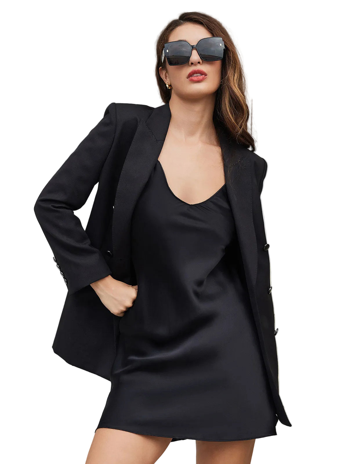 Femme portant la nuisette en soie noire, avec un décolleté subtil et une coupe élégante. L'ensemble est complété par un blazer noir et des lunettes de soleil, créant un look à la fois doux et sophistiqué.