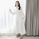 Peignoir femme Morwenna chaud et confortable, modèle long en tissu polaire blanc, avec ceinture à nouer et poches latérales, offrant douceur et chaleur pour des moments cocooning à la maison.