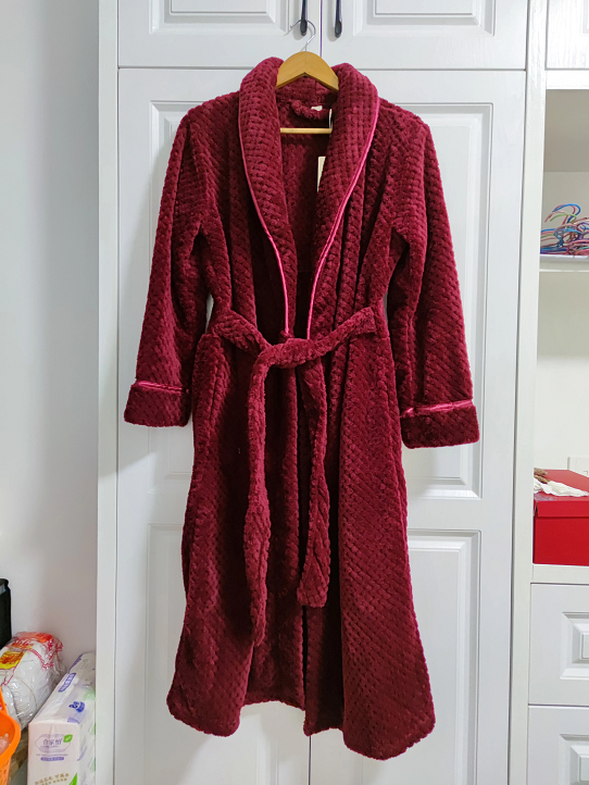 Peignoir femme Morwenna chaud et confortable, modèle long en tissu moelleux bordeaux avec ceinture et finitions contrastées, suspendu sur cintre.