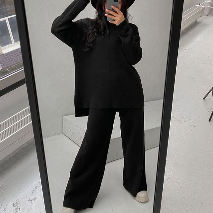 Femme prenant un selfie dans un miroir, vêtue de l’ensemble Naïla noir, composé d’un pull oversize à col montant et manches longues, et d’un pantalon large assorti. Tenue chaude, douce et élégante, idéale pour un look minimaliste et confortable au quotidien.