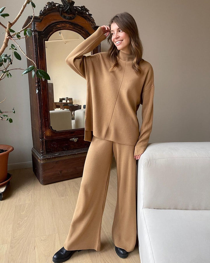 Femme souriante portant l’ensemble Naïla camel, composé d’un pull oversize à col montant et d’un pantalon large assorti. Tenue élégante, douce et chaude, parfaite pour un look cosy chic à la maison ou au quotidien.