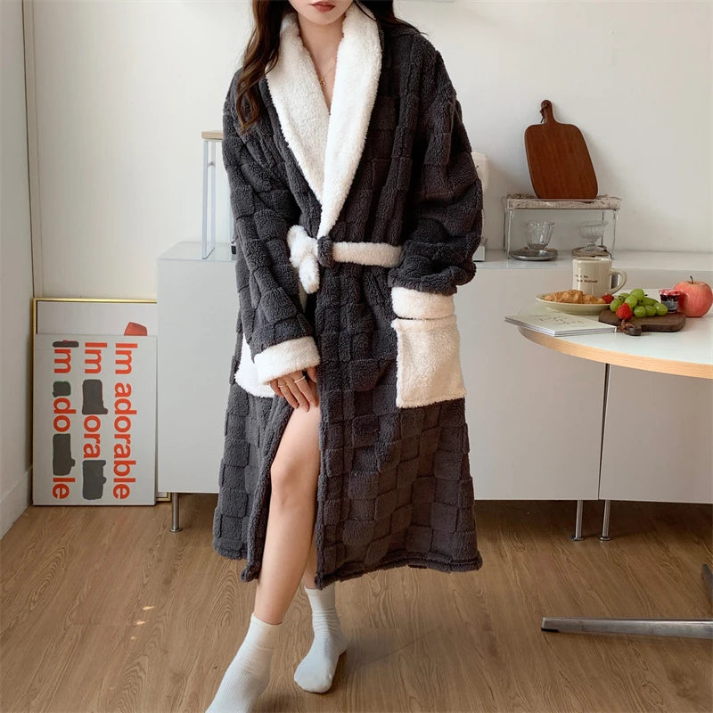 Peignoir femme chaud et confortable  Nancy  long en tissu peluche gris anthracite, col châle et poignets blancs, ceinturé avec poches contrastées, porté en intérieur.