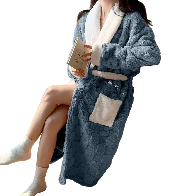 Peignoir femme chaud et confortable  Nancy en tissu peluche bleu avec col, poignets et ceinture blancs, grande poche contrastée, porté assise en intérieur avec un livre.