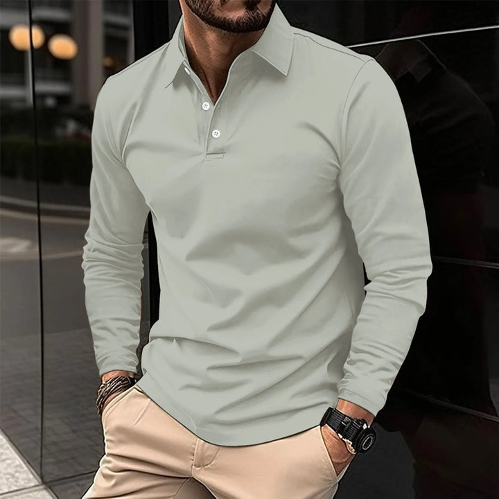 Polo à manches longues de couleur gris clair avec col classique et boutons blancs. Un choix élégant et confortable, parfait pour un look décontracté ou semi-formel, adapté à diverses occasions.