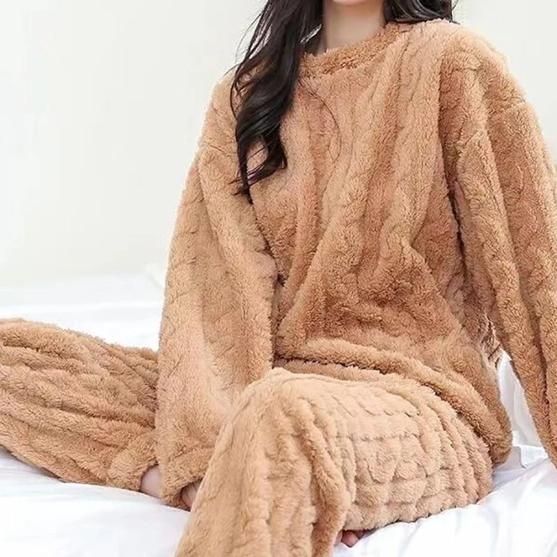 Femme assise sur un lit, vêtue d’un pyjama polaire camel avec motif torsadé, comprenant un haut à manches longues et un pantalon assorti. Ensemble chaud, ultra doux et confortable, idéal pour l’hiver et les journées cocooning à la maison.