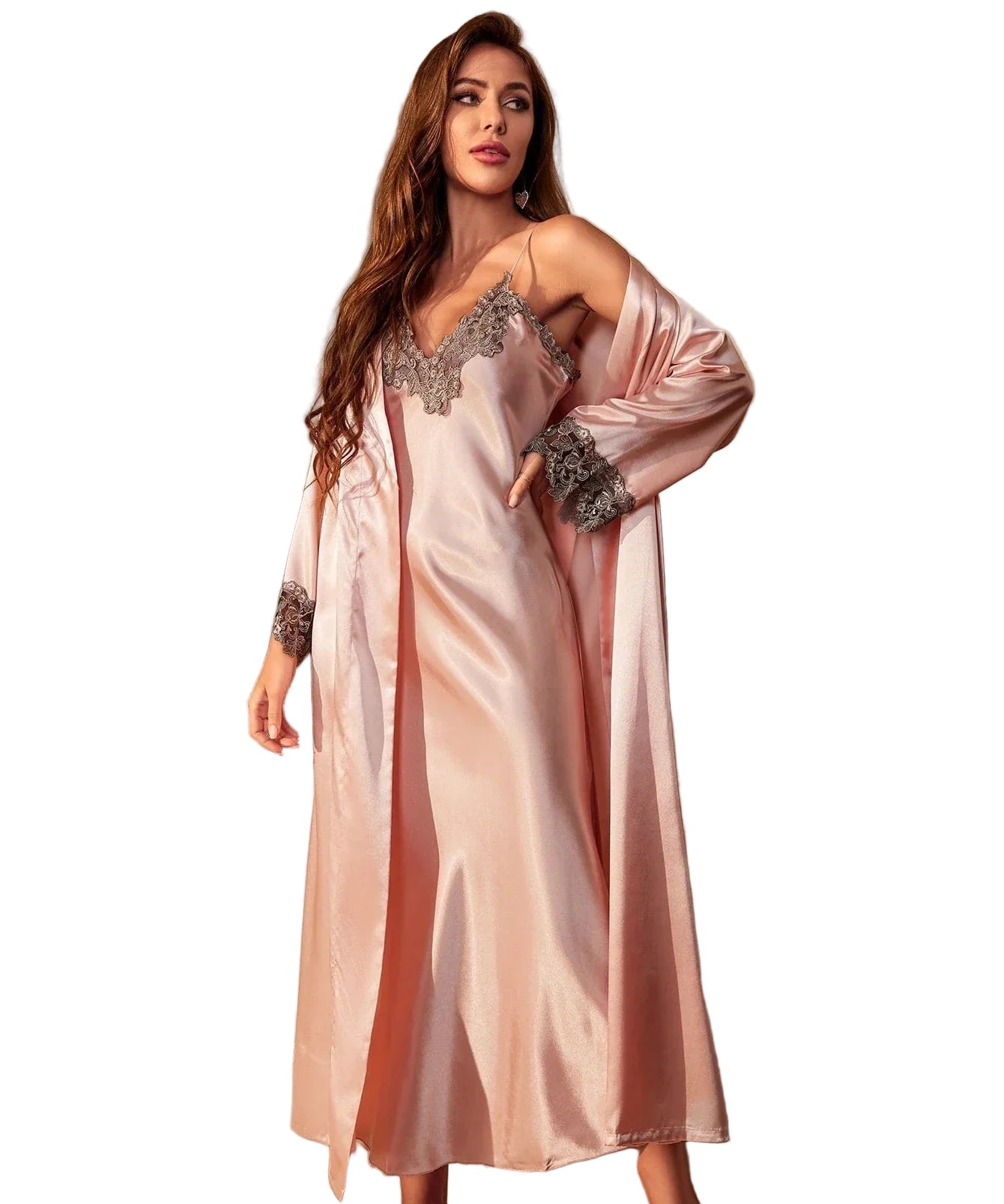 Femme portant une longue nuisette rose satinée avec fines bretelles, accompagnée d’un peignoir assorti. L’ensemble est orné de délicats détails en dentelle grise au col et aux manches. Lingerie raffinée, douce et confortable, idéale pour des soirées élégantes à la maison.