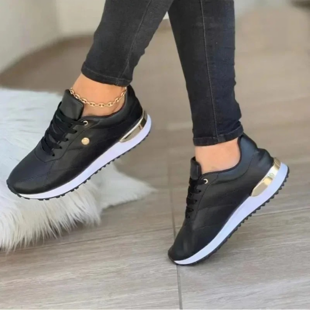 Baskets en cuir noir pour femme, avec un design chic et moderne. Les détails métalliques dorés et la semelle blanche épaisse offrent un contraste élégant. Parfaites pour le quotidien, elles combinent confort et style, idéales pour compléter vos tenues décontractées avec une touche sophistiquée.