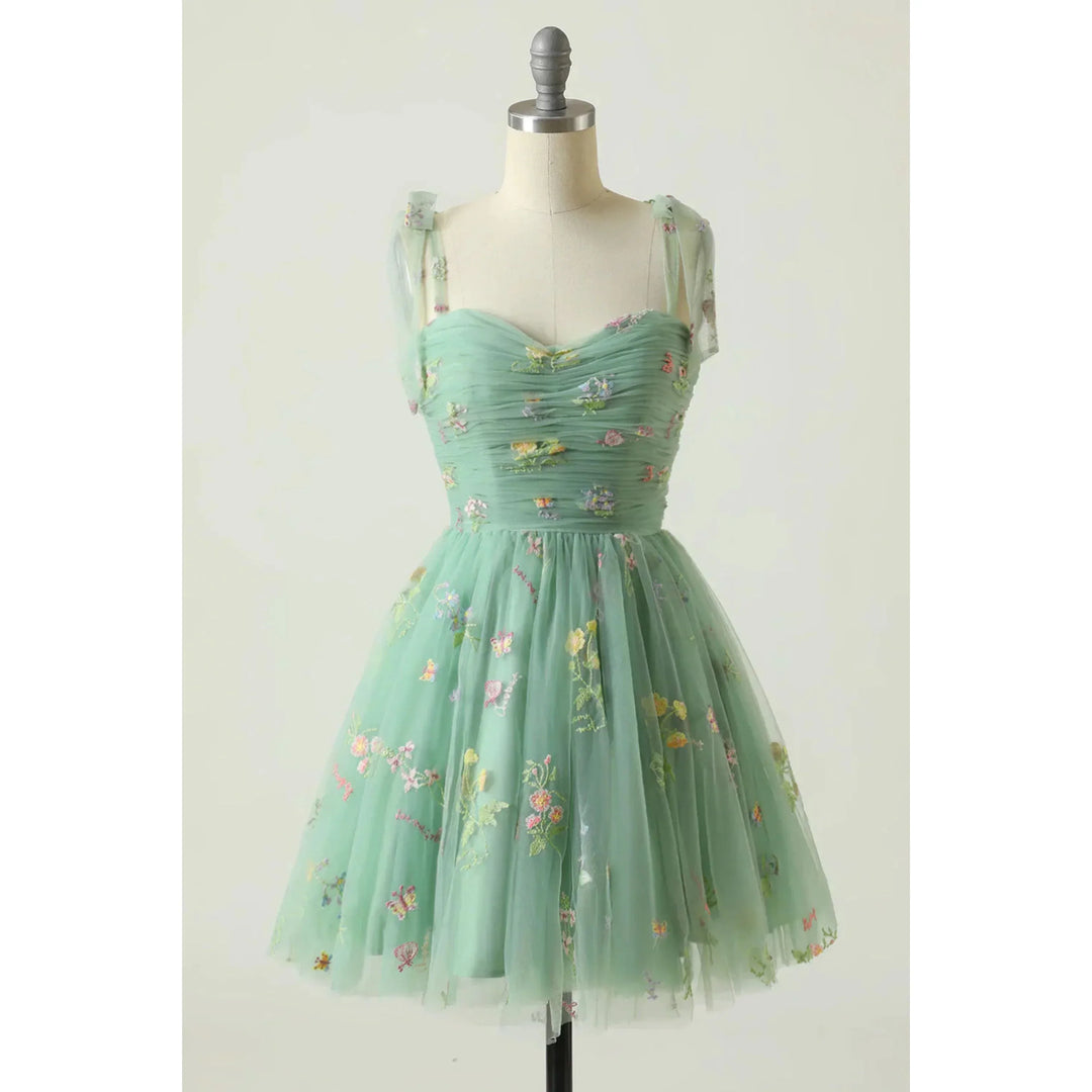Vert menthe en tulle brodé de fleurs, corsage plissé style bustier avec fines manches en voile, taille cintrée et jupe courte évasée, sur mannequin.