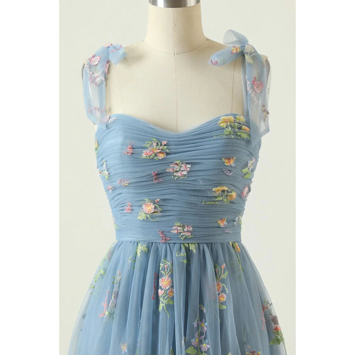 Bleu ciel  bustier plissé en tulle brodé de fleurs, bretelles en voile nouées et taille cintrée.