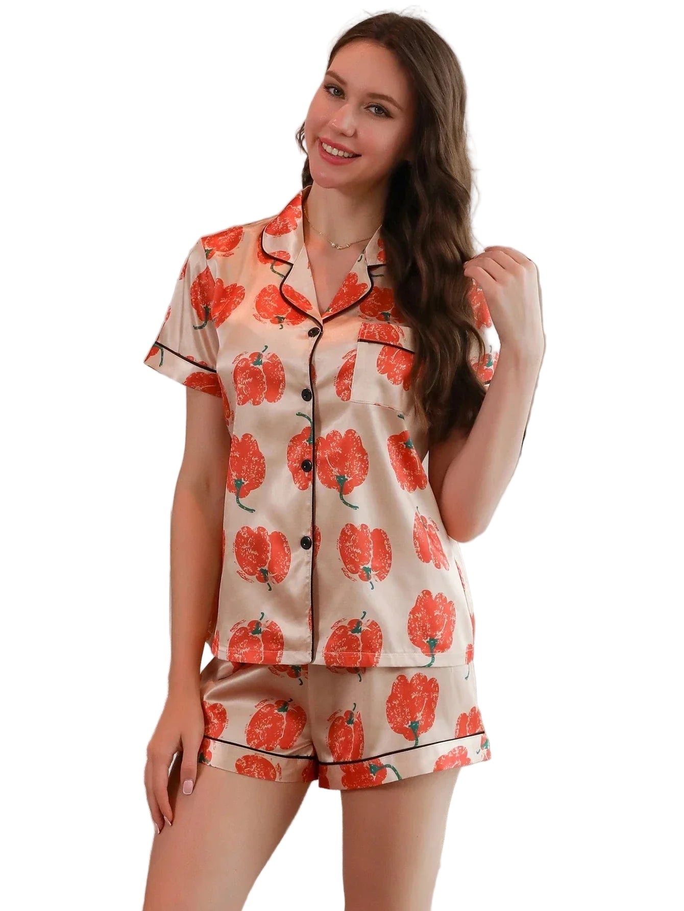 Femme portant le pyjama satin femme, un ensemble léger et élégant en satin beige, composé d’une chemise à manches courtes et d’un short assorti imprimés de grandes fleurs orange.