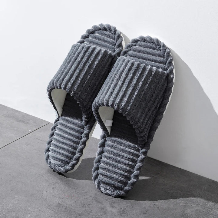 Chaussons modernes et élégants de couleur grise, conçus pour allier confort et style. Avec une bande moelleuse et une semelle en caoutchouc souple, ces chaussons ouverts sont parfaits pour un look décontracté à la maison. Idéals pour le quotidien, offrant un confort optimal et une grande durabilité.