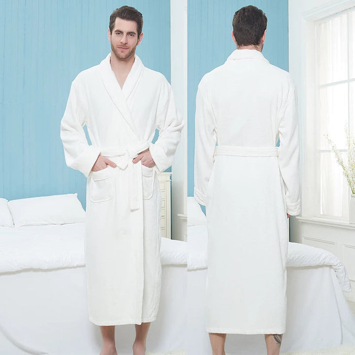 Homme portant le peignoir Pascal, modèle blanc épais et chaleureux, présenté de face et de dos dans une chambre lumineuse ; peignoir long avec ceinture et poches avant, idéal pour un confort douillet.