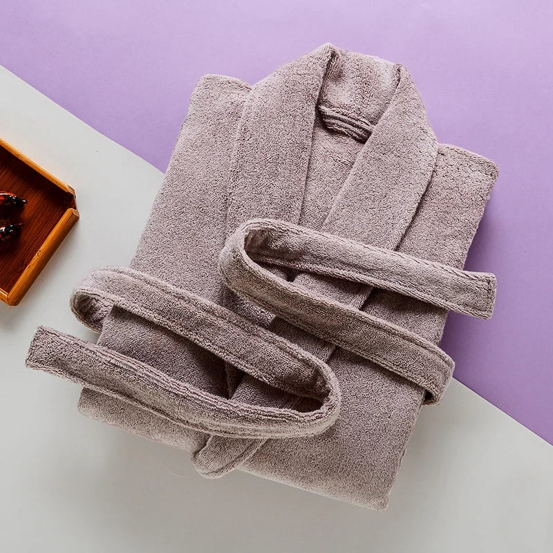Peignoir Pascal pour homme, modèle épais et chaleureux en tissu éponge beige, présenté soigneusement plié avec sa ceinture assortie sur un fond bicolore moderne.