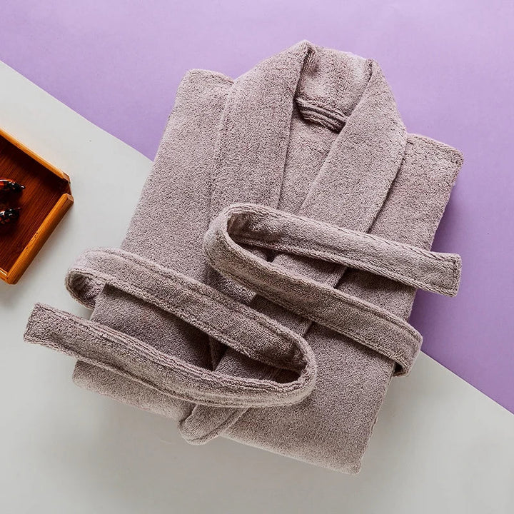 Peignoir Pascal pour homme, modèle épais et chaleureux en tissu éponge beige, présenté soigneusement plié avec sa ceinture assortie sur un fond bicolore moderne.