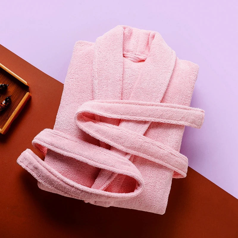 Peignoir Pascal pour homme, modèle épais et chaleureux en tissu éponge rose clair, présenté plié avec sa ceinture assortie sur un fond coloré moderne violet et terracotta.