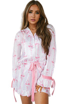 Pyjama femme Pascale blanc à motifs nœuds roses, chemise boutonnée à manches longues avec poignets noués, short assorti et ceinture à nouer, style élégant et raffiné en tissu léger.