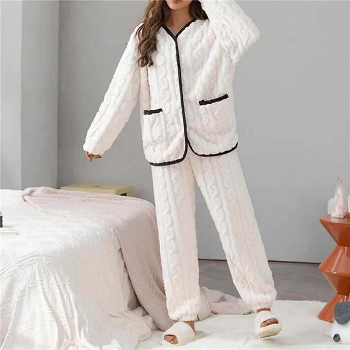 Femme portant le pyjama Percival, un ensemble d’hiver doux et chaud en tissu peluche ivoire, composé d’un haut à manches longues avec bordures noires et d’un pantalon assorti, idéal pour rester confortable à la maison.