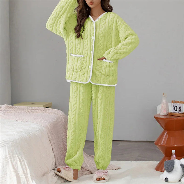 Femme portant le pyjama Percival, un ensemble d’hiver doux et chaud en tissu peluche vert clair, avec un haut boutonné à manches longues bordé de blanc et un pantalon assorti, idéal pour rester au chaud et confortable à la maison.