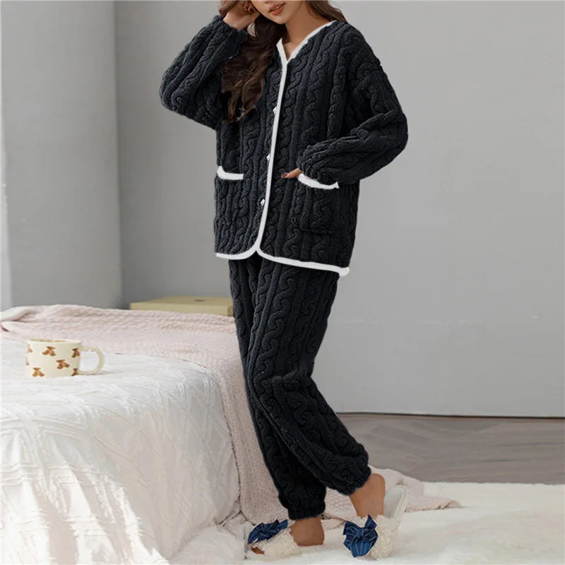 Femme portant le pyjama Percival, un ensemble d’hiver doux et chaud en tissu peluche noir, composé d’un haut boutonné à manches longues bordé de blanc et d’un pantalon assorti, parfait pour rester bien au chaud à la maison.