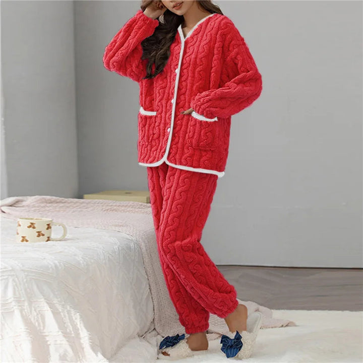 Femme portant le pyjama Percival, un ensemble d’hiver doux et chaud en tissu peluche rouge, composé d’un haut boutonné à manches longues bordé de blanc et d’un pantalon assorti, idéal pour rester bien au chaud et confortable à la maison.
