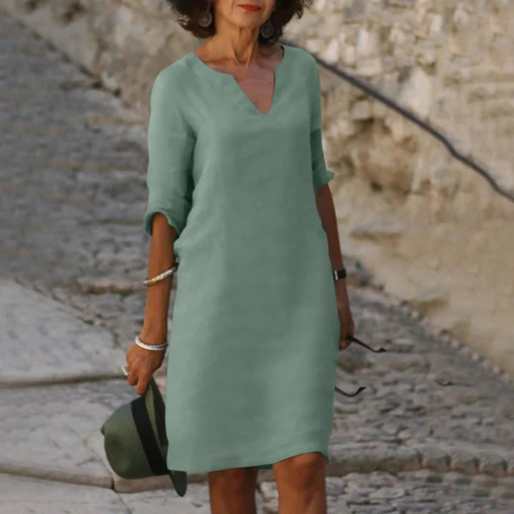 Portée en extérieur, coupe droite au-dessus du genou, col en V et manches 3/4 retroussées, style minimaliste et léger.