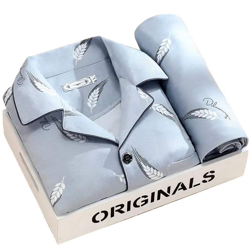 Pyjama premium pour homme présenté plié dans une boîte, en tissu bleu clair doux et respirant, avec motifs discrets de plume. Ensemble élégant et très confortable, idéal pour un sommeil agréable.