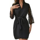 Kimono femme Quitterie noir, coupe élégante avec ceinture à nouer et manches en dentelle, porté en intérieur dans une chambre lumineuse, style raffiné et séduisant.