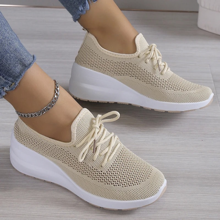 Baskets beige en maille respirante avec lacets et semelle compensée blanche, portées avec jean, vue rapprochée en intérieur.