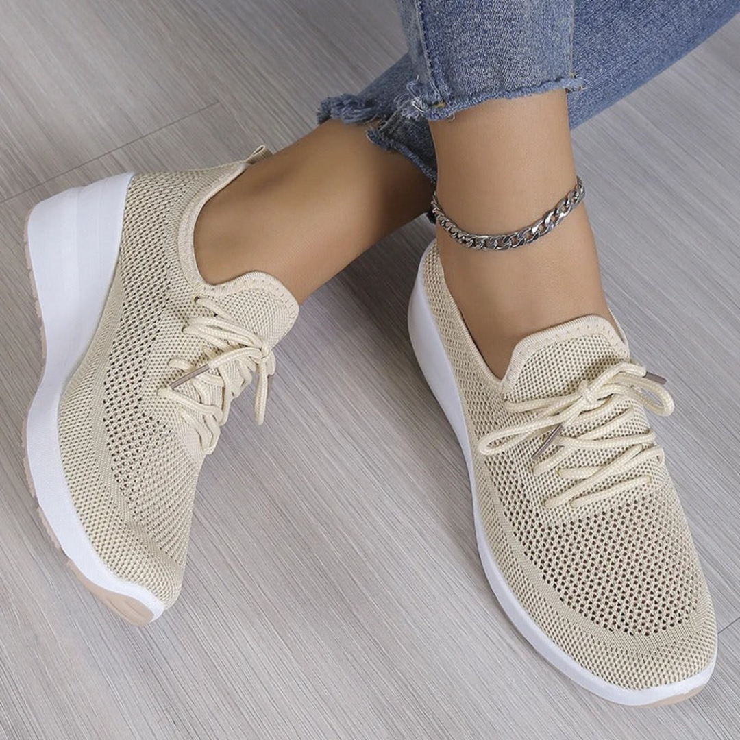 Baskets beige en maille respirante avec lacets et semelle compensée blanche, portées avec un jean, vue en plongée.