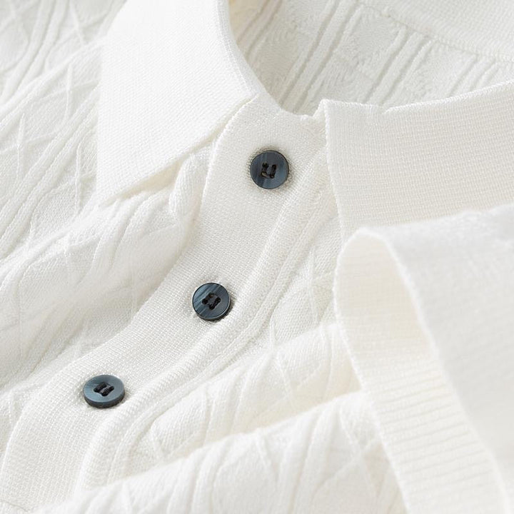Détail du col et des boutons noirs qui ajoutent une touche sophistiquée à ce polo blanc en maille, idéal pour un look à la fois chic et décontracté.