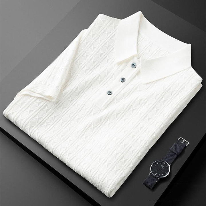 Polo blanc soigneusement plié avec des détails de boutons noirs, accompagné d&