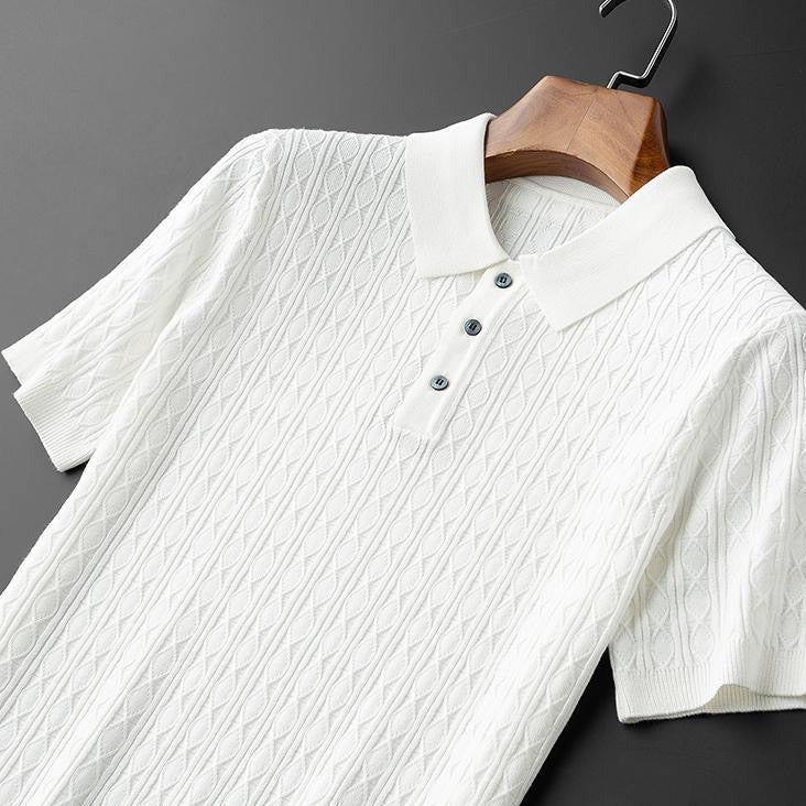 Polo blanc suspendu, avec un col raffiné et des boutons noirs contrastés, offrant un design moderne et une texture en maille élégante.