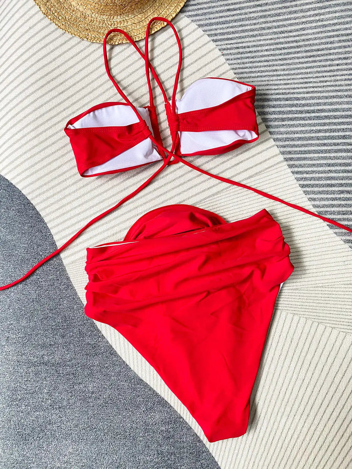 Ce bikini rouge à design chic, avec son haut à bandes croisées et son bas taille haute, incarne l&