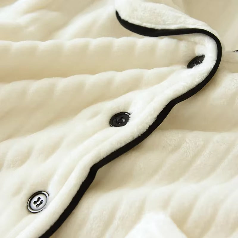 Gros plan sur la matière douce et moelleuse d’un pyjama pour femme de couleur crème, avec boutons noirs et bordure contrastée. Modèle Renée, chaud et confortable, idéal pour les soirées cocooning d’hiver.