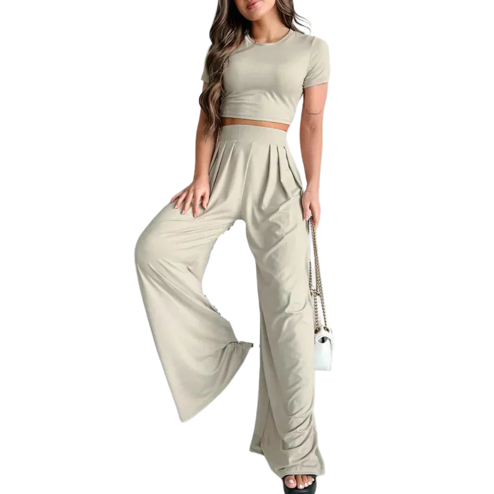 Femme portant l’ensemble Rosalind beige clair, composé d’un crop top à manches courtes et d’un pantalon taille haute large fluide. Tenue légère et confortable, parfaite pour l’été, les journées décontractées ou un look chic et décontracté.