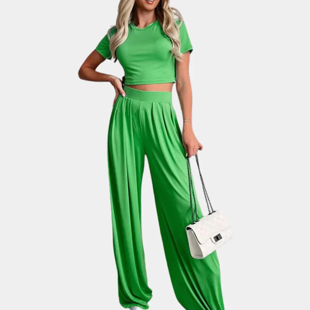 Femme portant l’ensemble Rosalind vert vif, composé d’un crop top à manches courtes et d’un pantalon large fluide taille haute. Tenue légère, confortable et tendance, idéale pour les journées décontractées ou un look estival stylé.