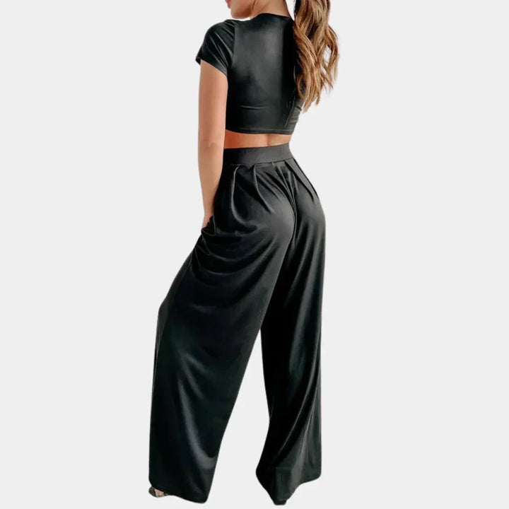 Vue arrière d’une femme portant l’ensemble Rosalind noir, composé d’un crop top à manches courtes et d’un pantalon large taille haute fluide. Tenue légère et élégante, idéale pour un style décontracté tout en restant sophistiqué.