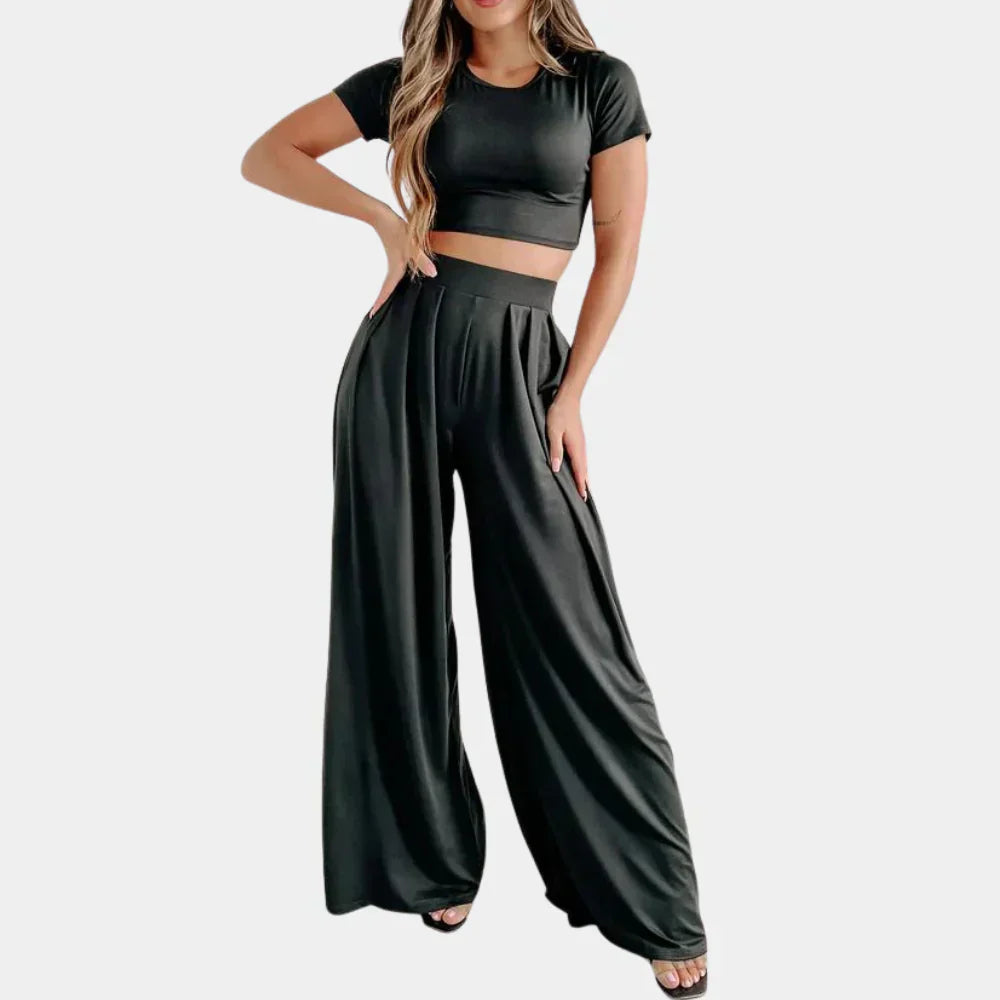 Femme portant l’ensemble Rosalind noir, composé d’un crop top à manches courtes et d’un pantalon palazzo taille haute fluide. Tenue légère, confortable et élégante, parfaite pour un look casual chic de jour comme de nuit.